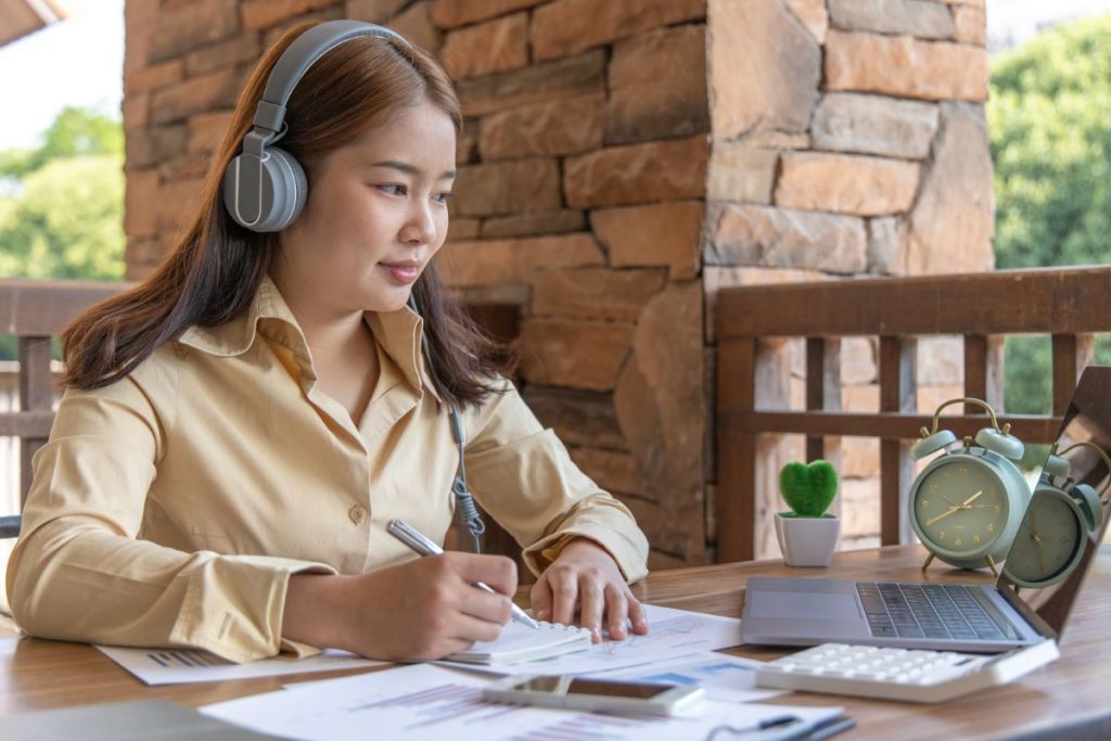 Mulher estudando por vídeo aula e fazendo anotações